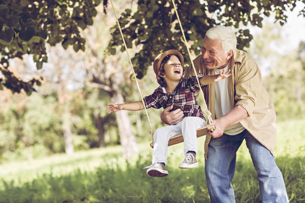Grandfather pushing his grandson on a swing